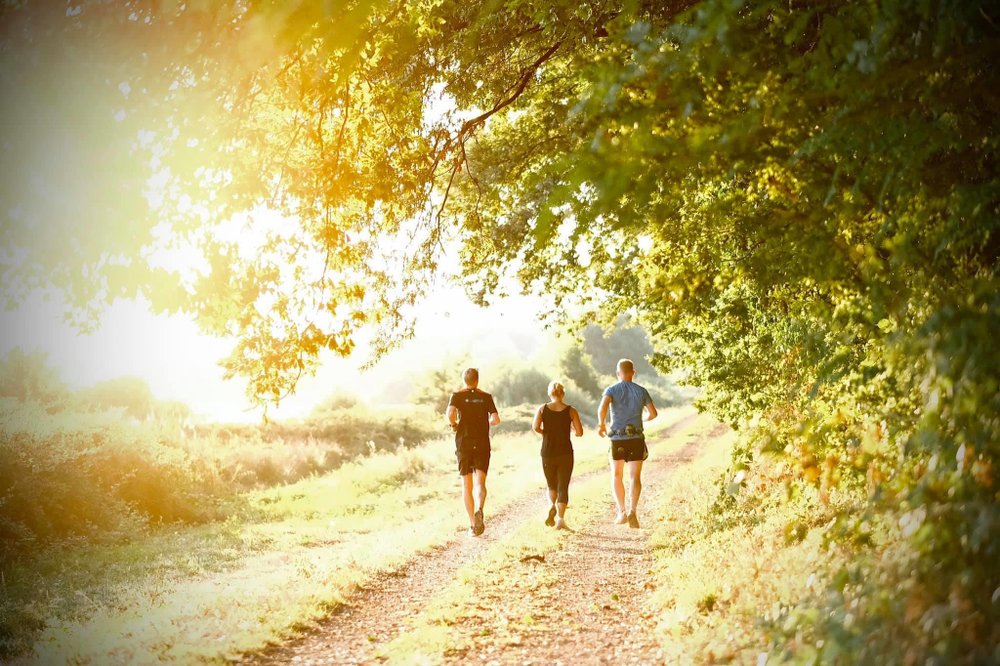 3 personer springer längs en väg i naturen.