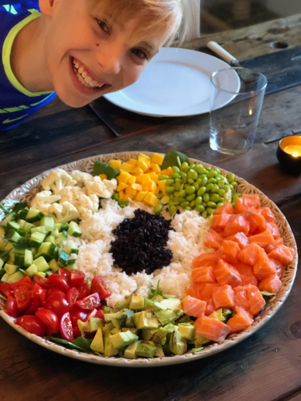 Glad kille framför en stor poké bowl